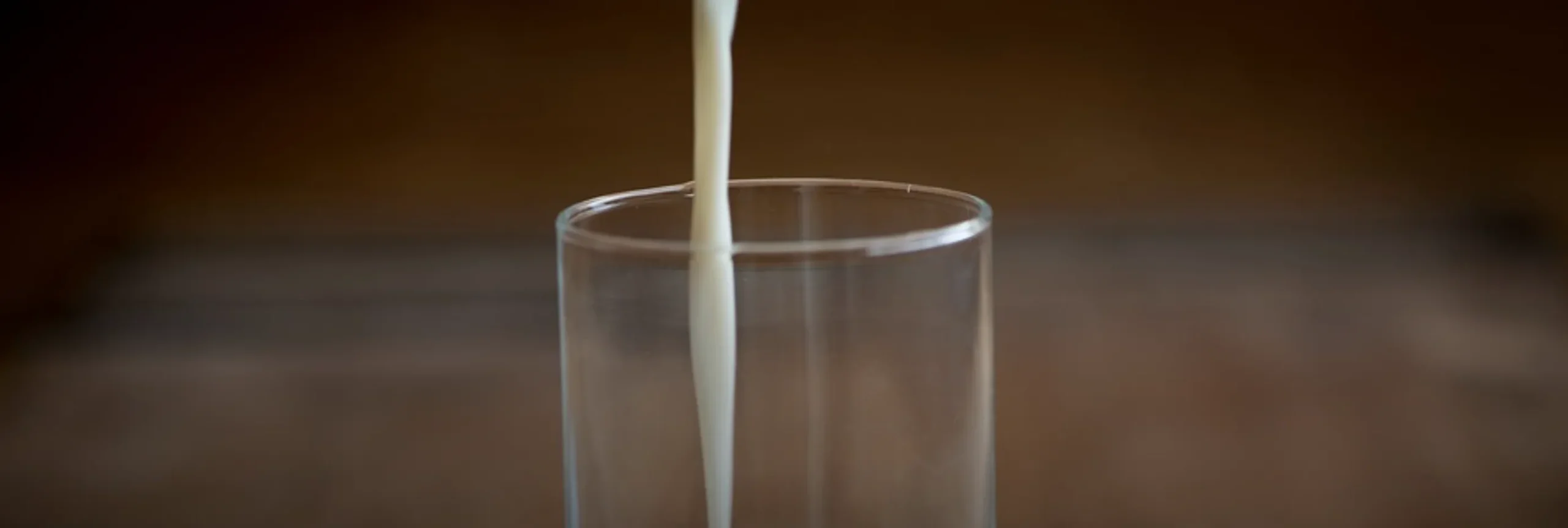 Close up de vaso con leche vertida.