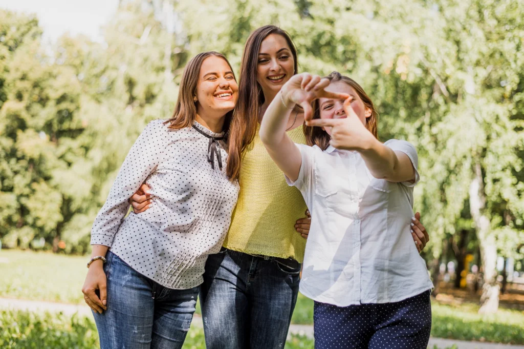 Tres amigas felices en un parque sonriendo juntas.