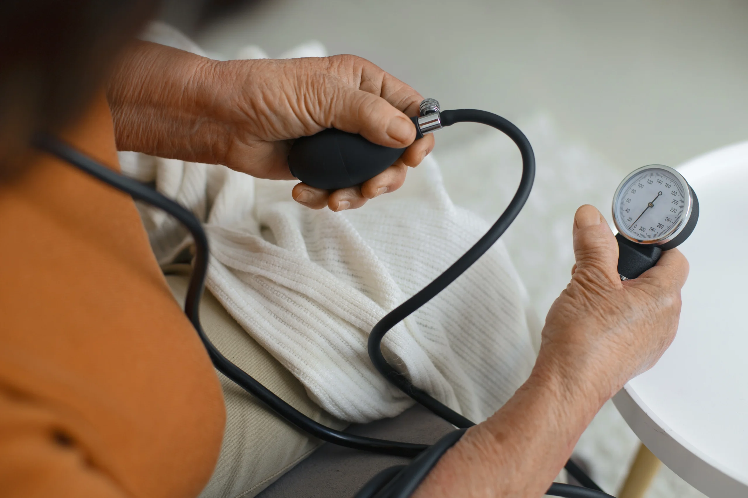 Consulta médica integrativa: paciente mayor midiendo su presión arterial en consulta médica